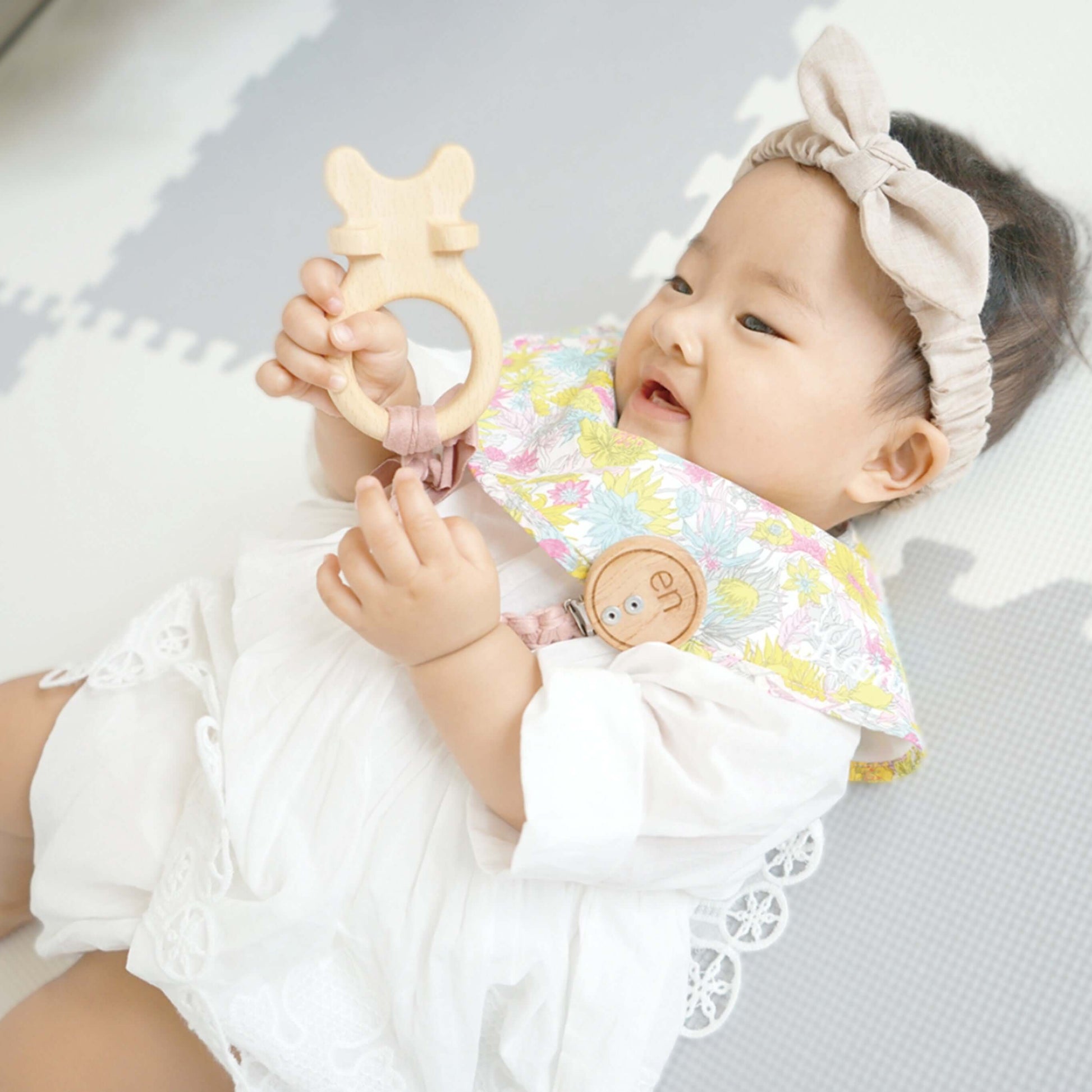 赤ちゃんが歯固め en ナチュラルを持って笑顔で遊んでいる姿