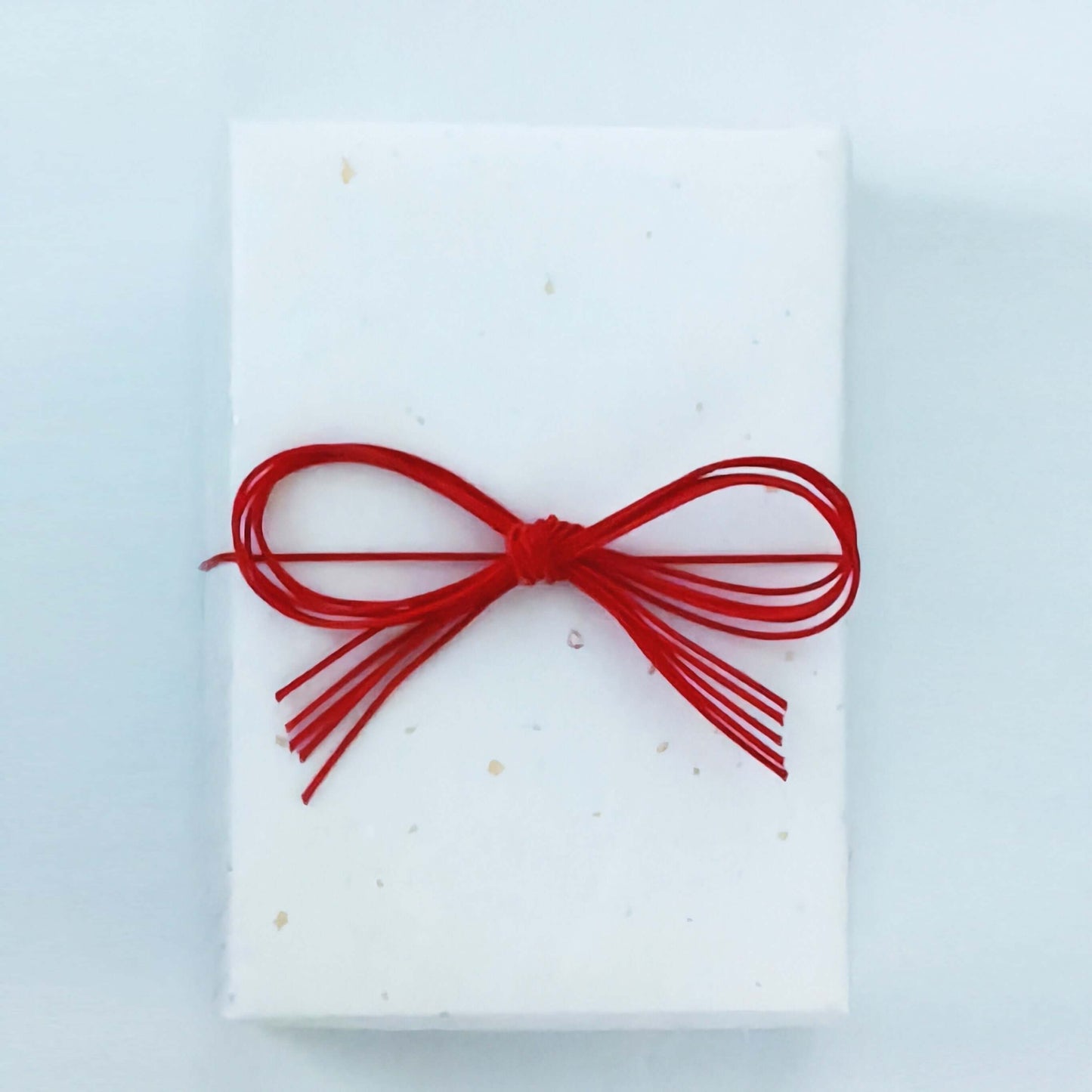 ギフトラッピングされた白い箱に赤いリボンが結ばれています。出産祝い向けの特別な包装。