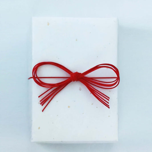 ギフトラッピングされた白い箱に赤いリボンが結ばれています。出産祝い向けの特別な包装。